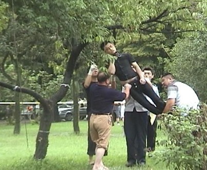 首吊り自殺した黒い服の男の死体を下ろす風景