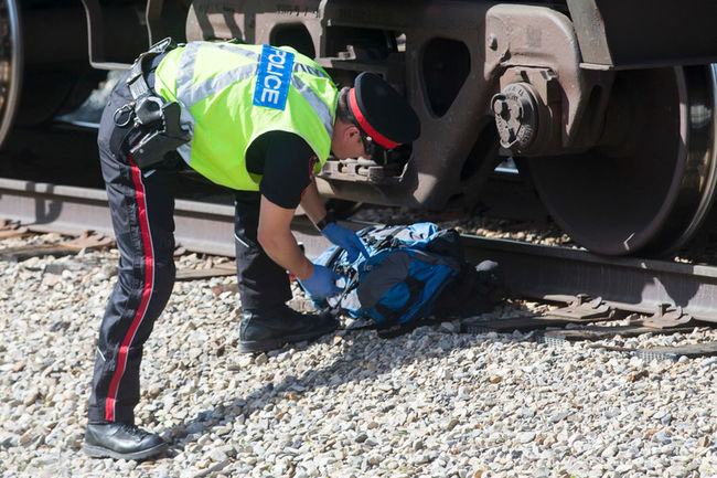 電車への飛び込み自殺者の遺品を調べる警官